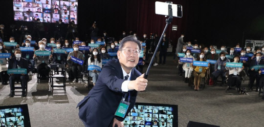 이재명 더불어민주당 대선후보가 29일 광주시 서구 김대중컨벤션센터에서 열린 전국민 선대위회의에서 참석자들과 함께 셀카봉으로 직접 기념촬영을 하고 있다. <연합뉴스>